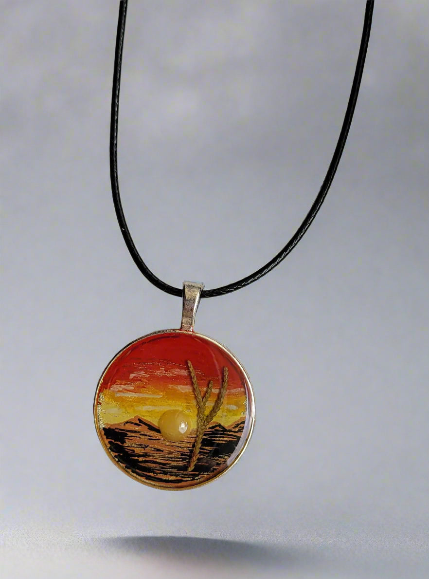 Necklace with a pendant featuring a sunset design on a marble surface