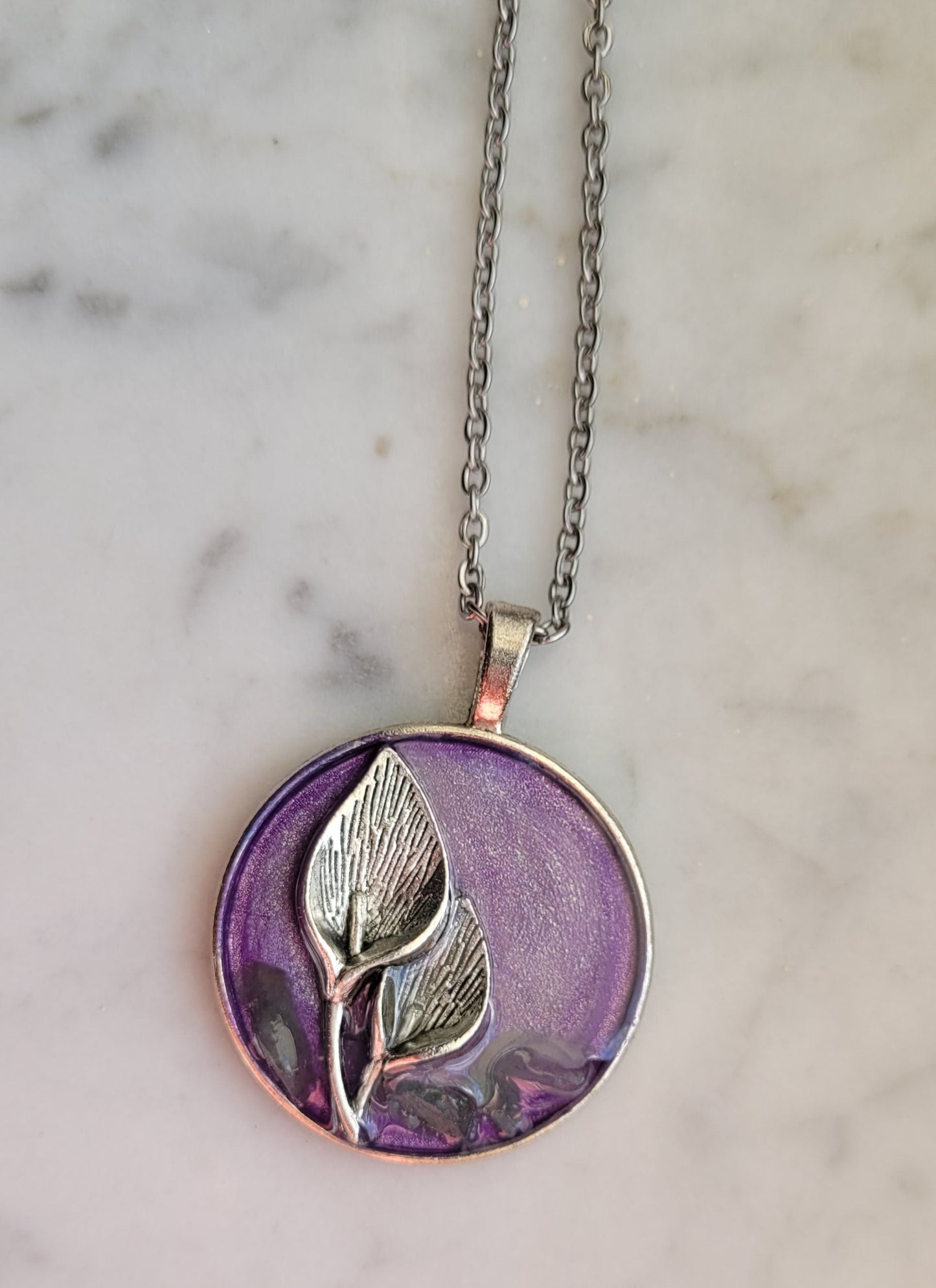 Necklace with a purple pendant featuring leaf designs on a marble background