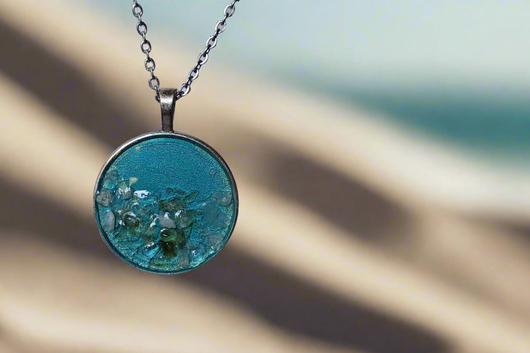 Necklace with a blue pendant on a sandy background
