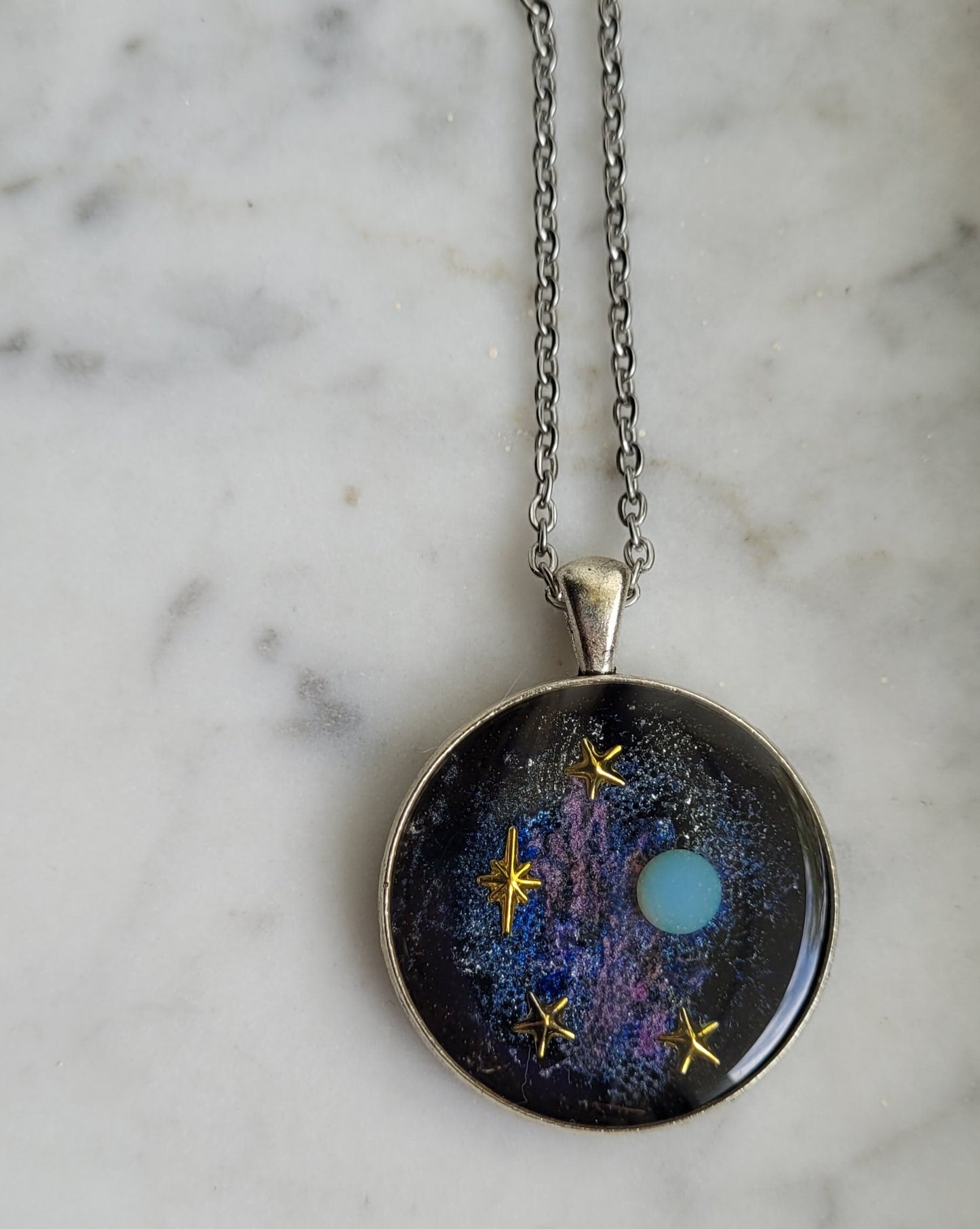 Necklace with a round pendant featuring a celestial design on a marble surface