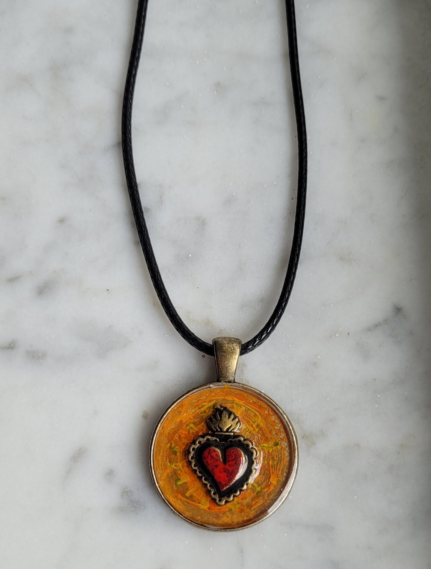 Necklace with a circular pendant featuring a heart design on a marble surface