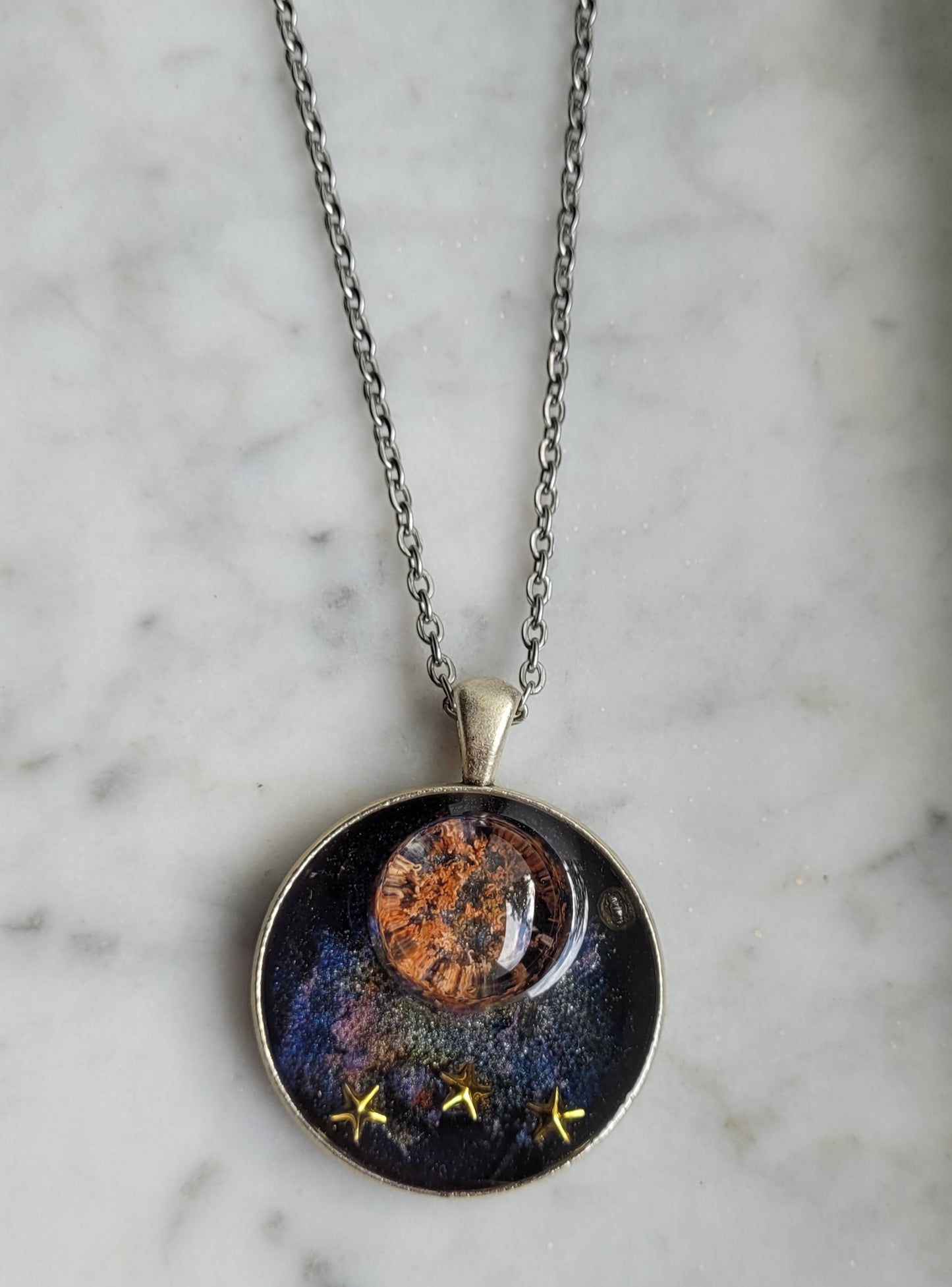 Necklace with a round pendant featuring celestial design on a marble surface