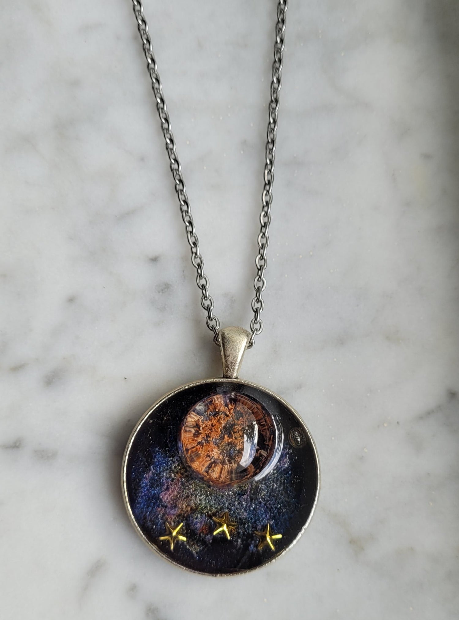 Necklace with a round pendant featuring celestial design on a marble surface