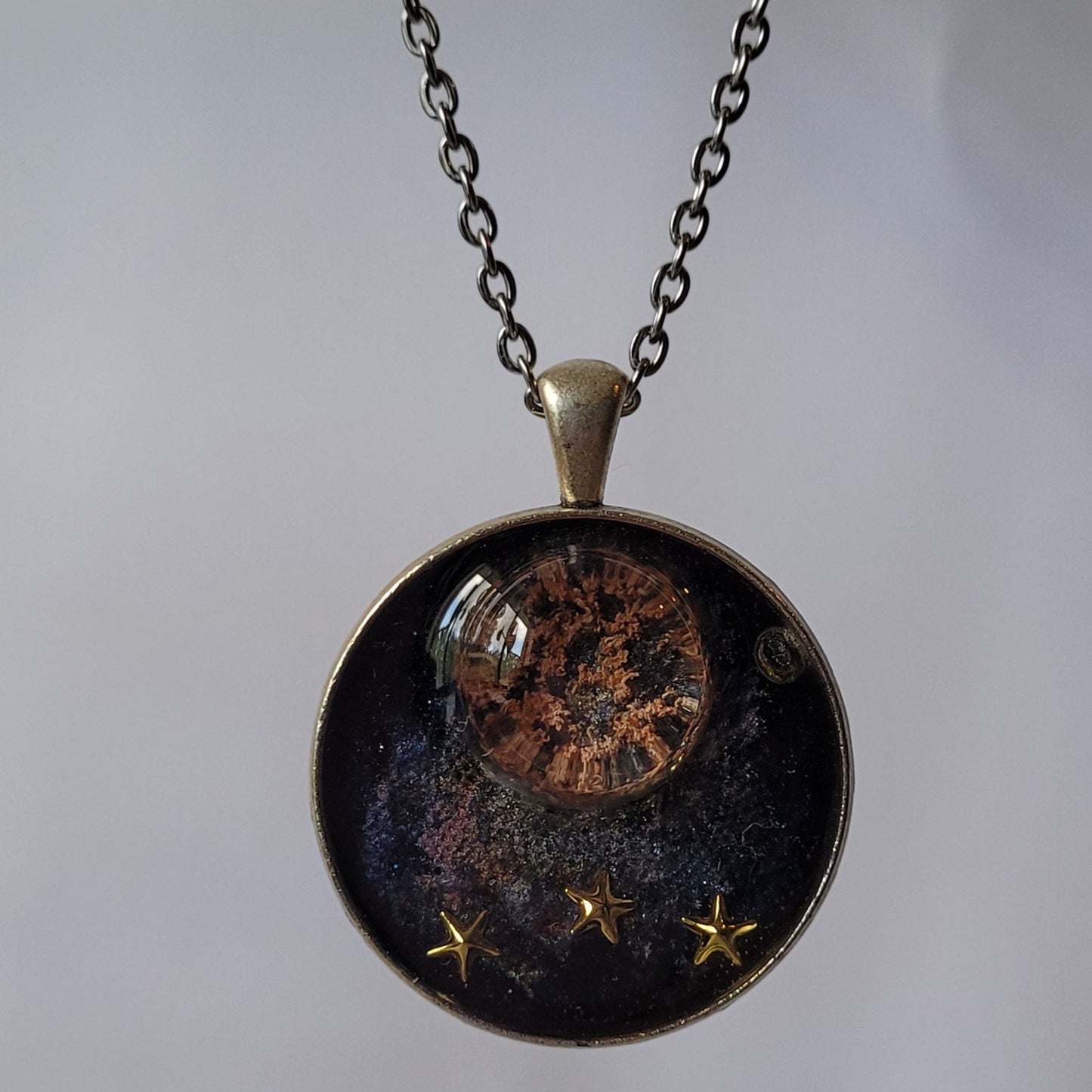 Necklace with a round pendant featuring celestial design on a light gray background
