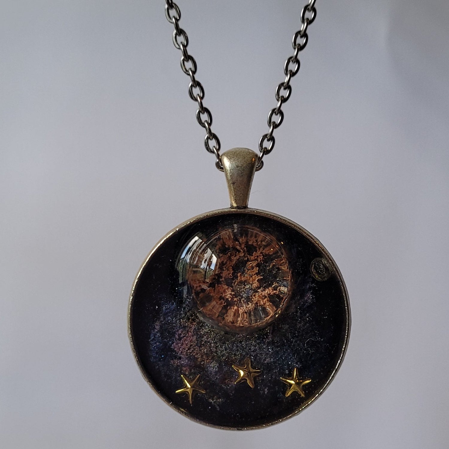 Necklace with a round pendant featuring celestial design on a light gray background