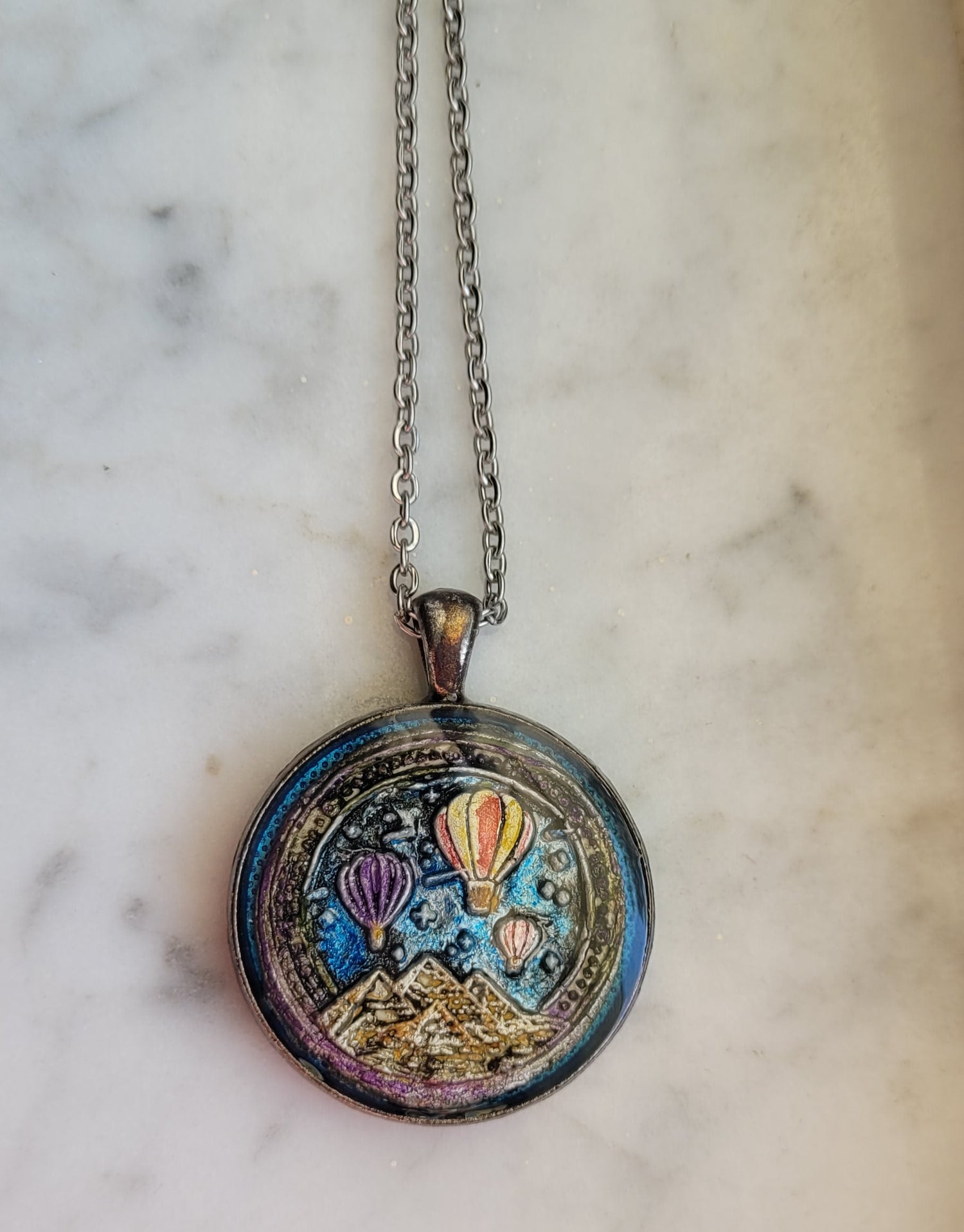 Decorative locket with celestial design on a marble surface