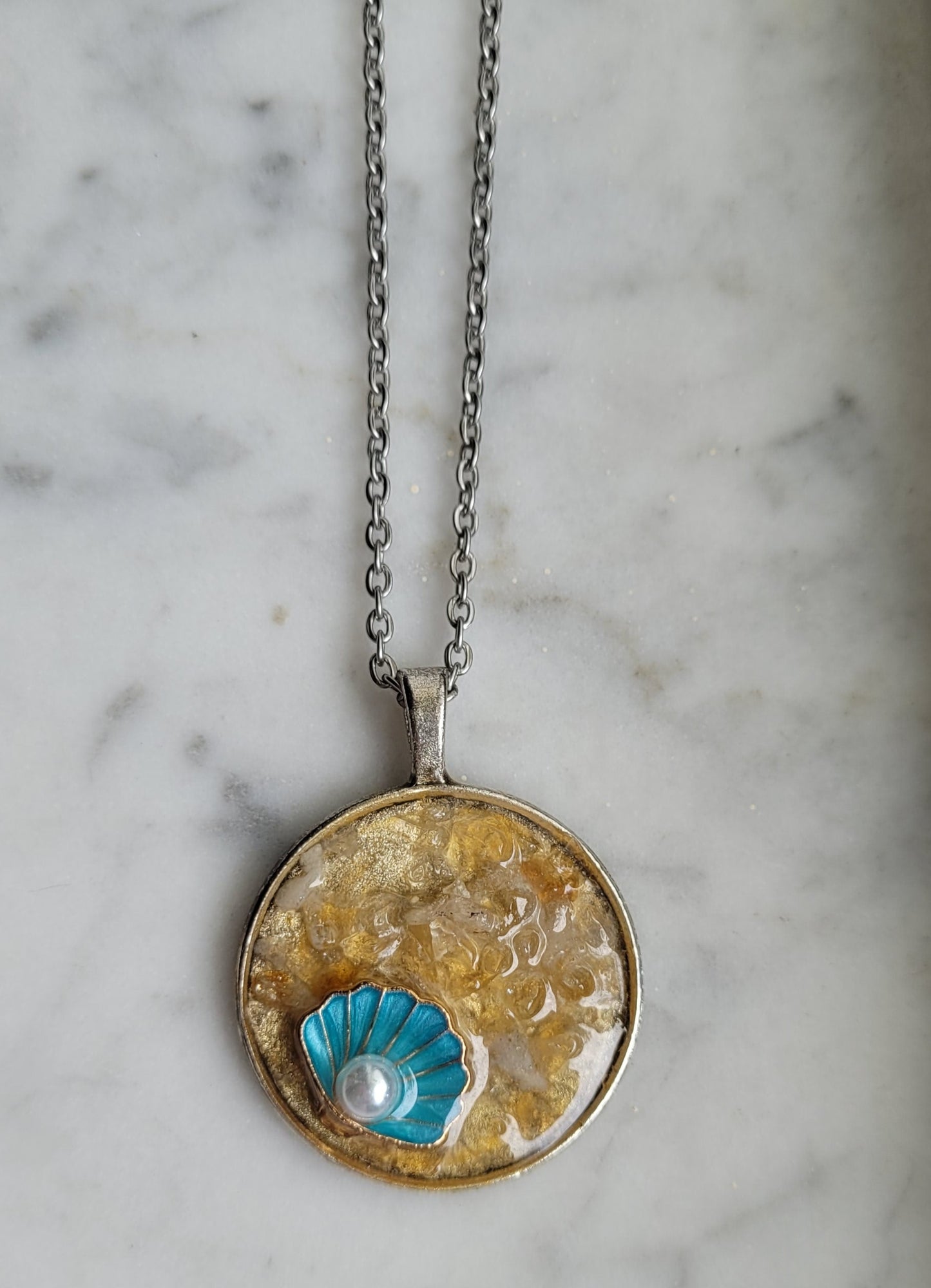 Necklace with a round pendant featuring a blue flower design on a marble background