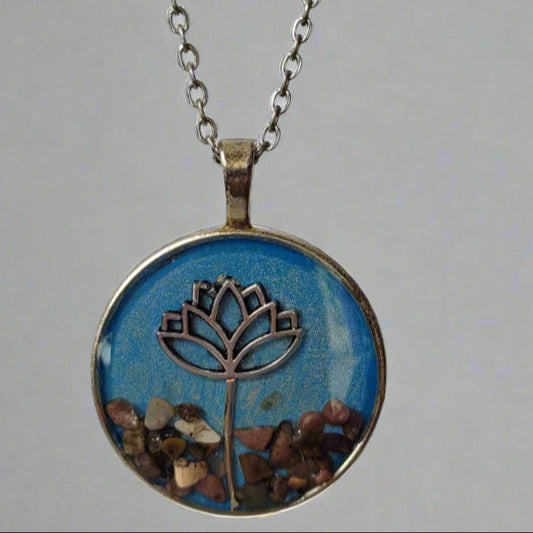Necklace with a round pendant featuring a lotus design and embedded stones on a gray background