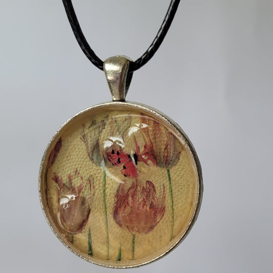 Round pendant with floral design on a thin black cord against a light gray background