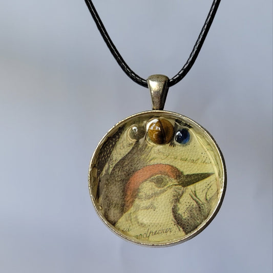 Silver pendant on a black cord against a white background