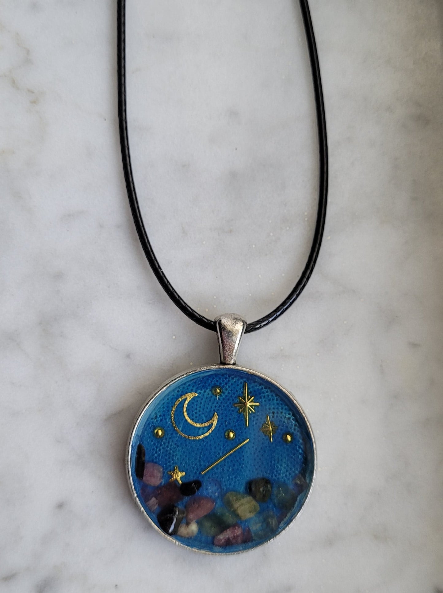 Necklace with a pendant featuring celestial design on a marble surface