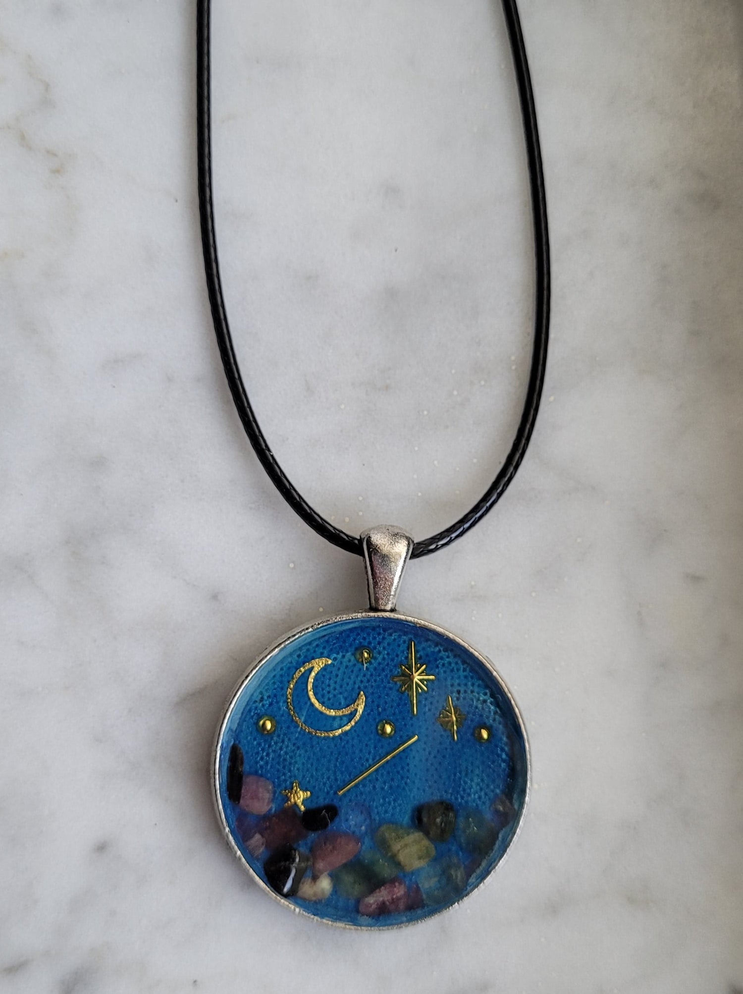 Necklace with a pendant featuring celestial design on a marble surface