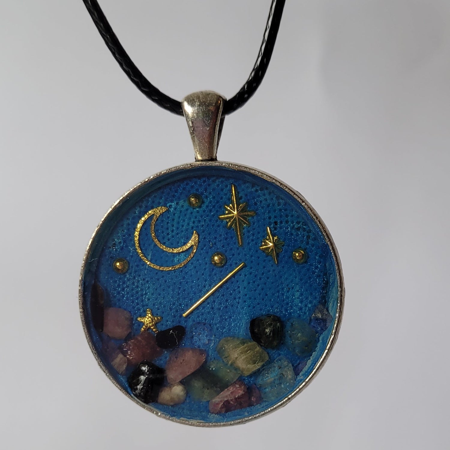 Necklace with a round pendant featuring celestial designs on a plain background