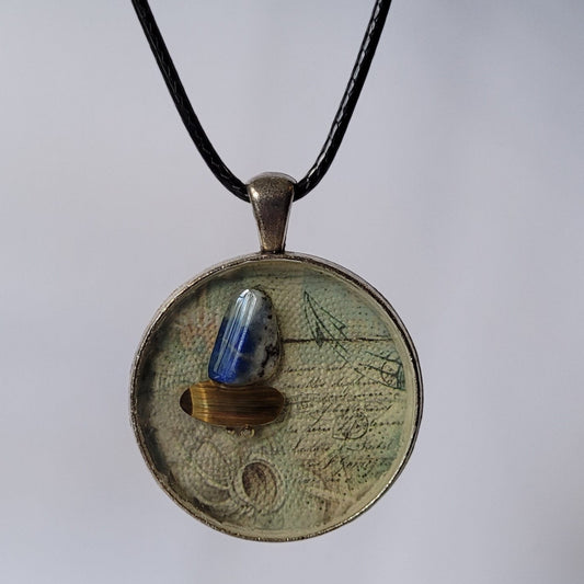 Round pendant with a blue stone on a black cord against a white background