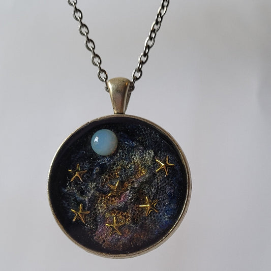 Necklace with a round pendant featuring a celestial design on a plain background